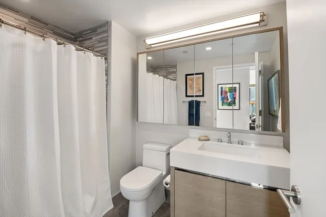 a bathroom with a sink mirror and a toilet