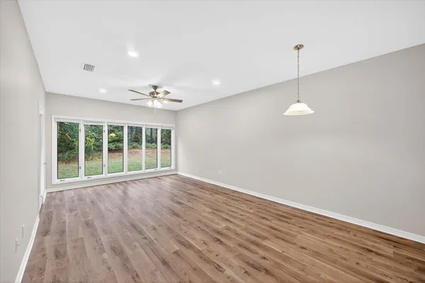 a view of an empty room with a window and wooden floor