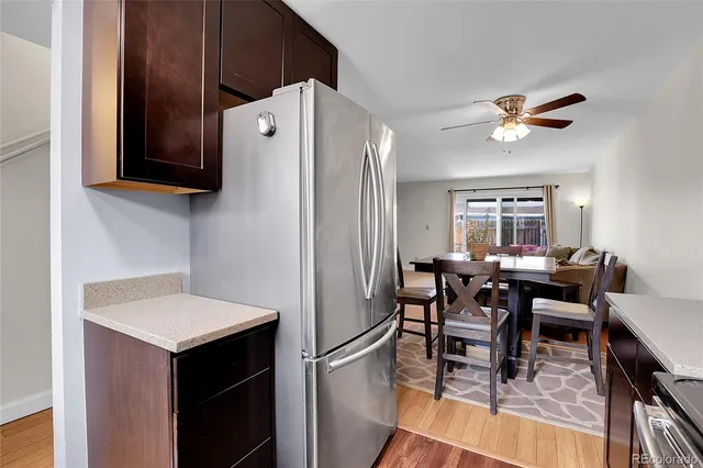 a kitchen with stainless steel appliances granite countertop a dining table chairs and a refrigerator