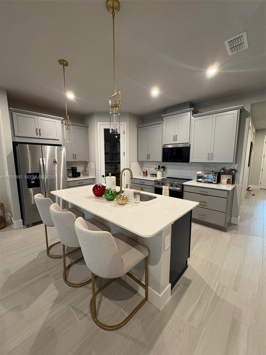 5020 124th Avenue East Parrish, FL 34219 - Photo 8 of 25 a kitchen with stainless steel appliances kitchen island granite countertop a sink a stove a refrigerator cabinets and chairs