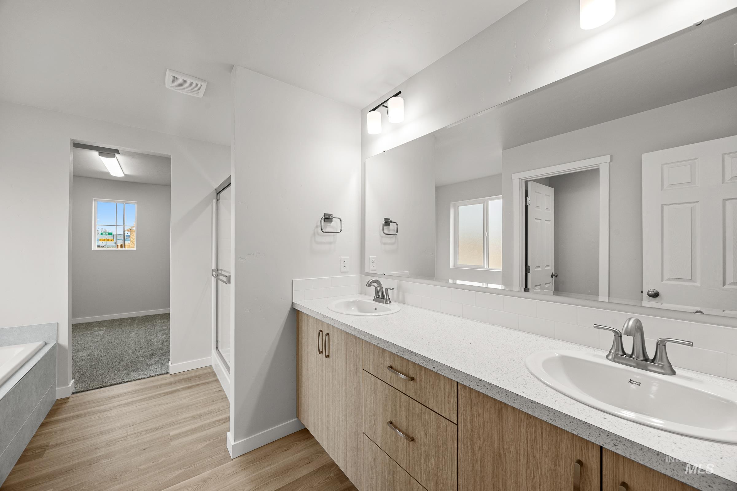 13654 Inman Court Caldwell, ID 83607 - Photo 21 of 25 Full bathroom with double vanity, a bath, light wood-style flooring, and a shower stall