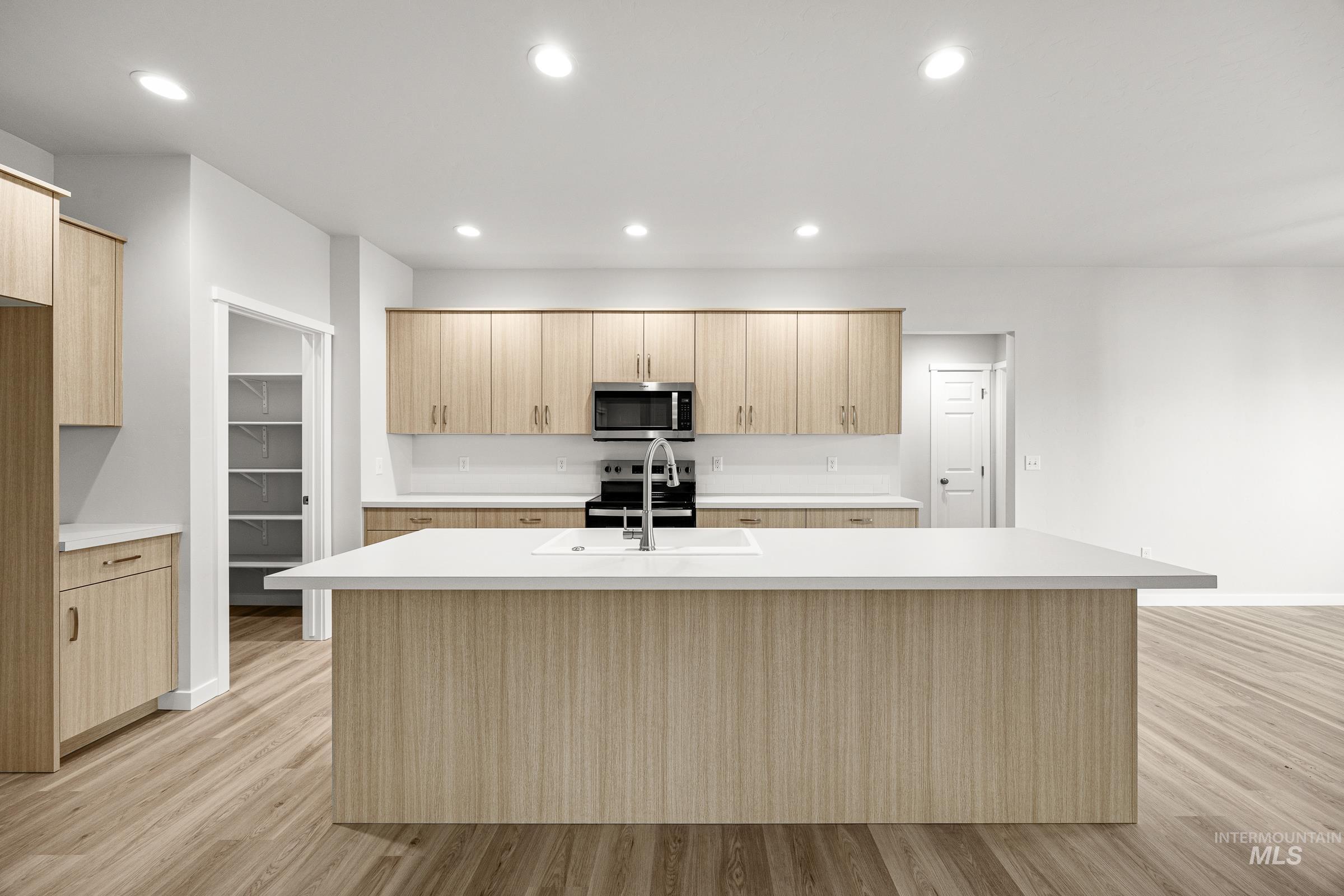 13654 Inman Court Caldwell, ID 83607 - Photo 3 of 25 Kitchen with light wood finish cabinetry, a center island with sink, stainless steel appliances, light wood-style floors, and recessed lighting