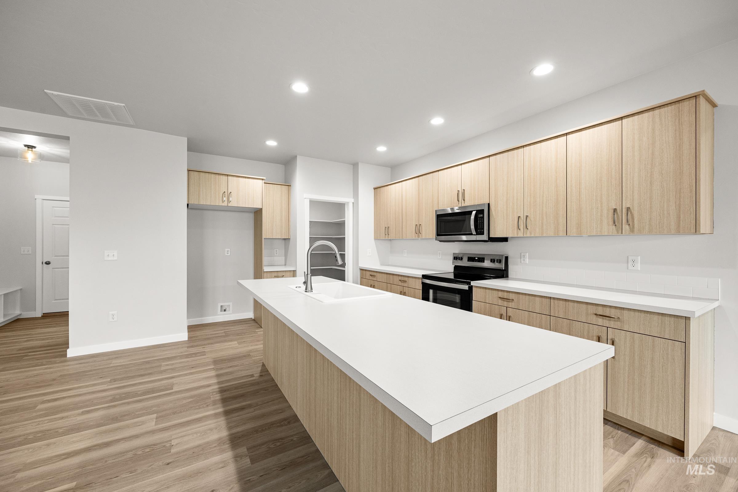 13654 Inman Court Caldwell, ID 83607 - Photo 4 of 25 Kitchen with light wood finish cabinetry, stainless steel appliances, light countertops, recessed lighting, and light wood finished floors