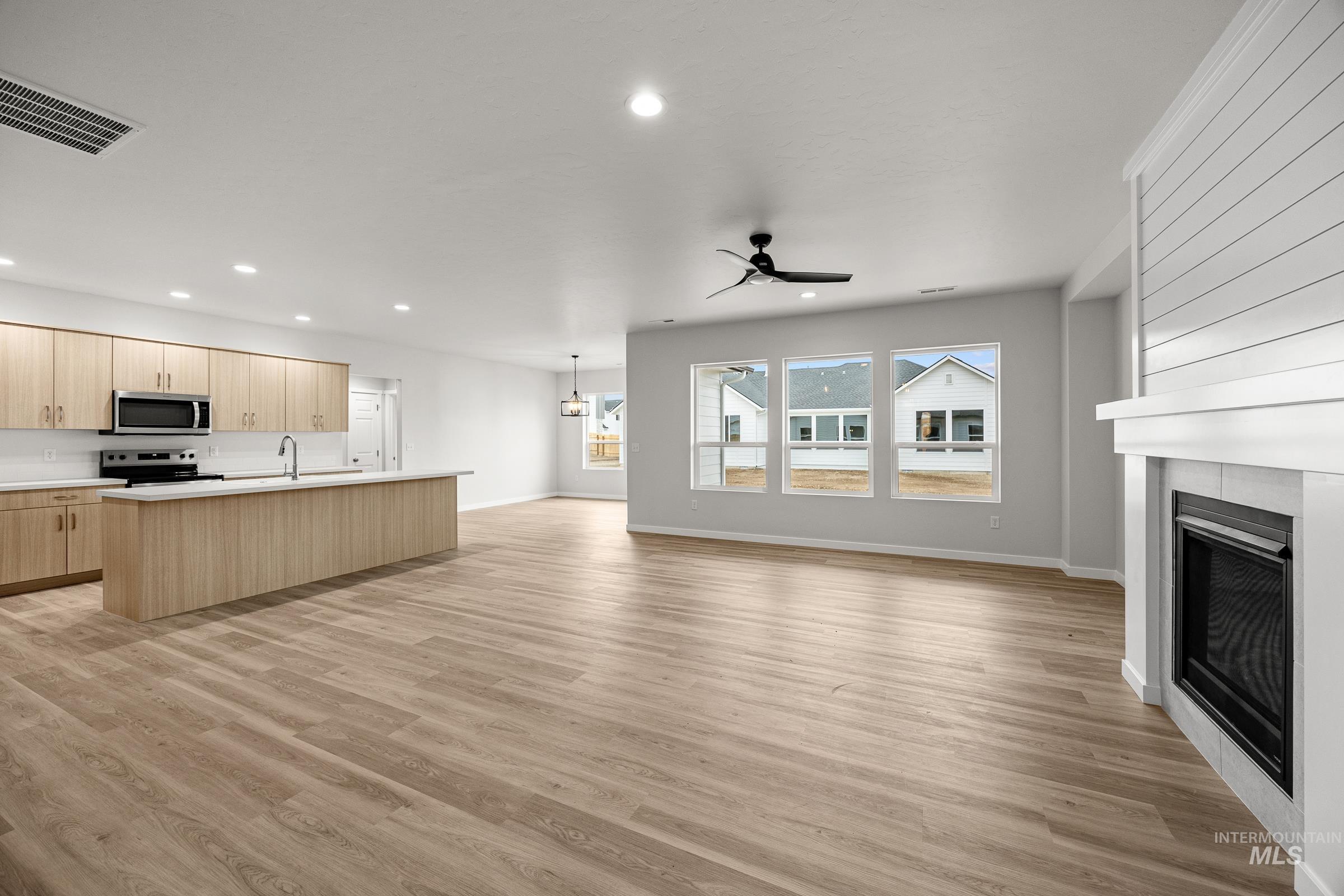 13654 Inman Court Caldwell, ID 83607 - Photo 7 of 25 Unfurnished living room with ceiling fan, a fireplace, light wood finished floors, and suspended lighting