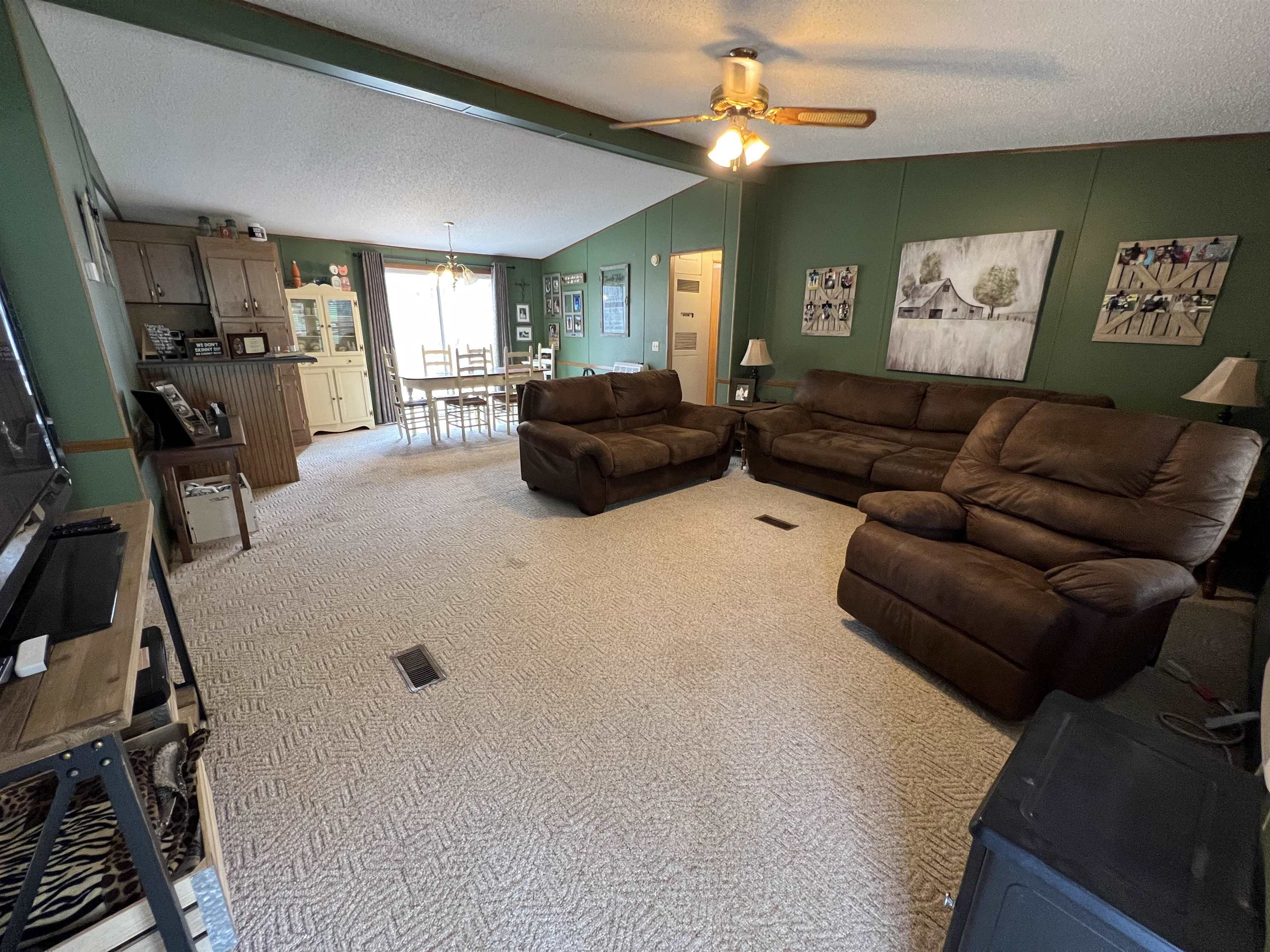 1405 Bruton Branch Road Savannah, TN 38372 - Photo 10 of 20 Living room with a textured ceiling, visible vents, ceiling fan with notable chandelier, vaulted ceiling with beams, and light colored carpet