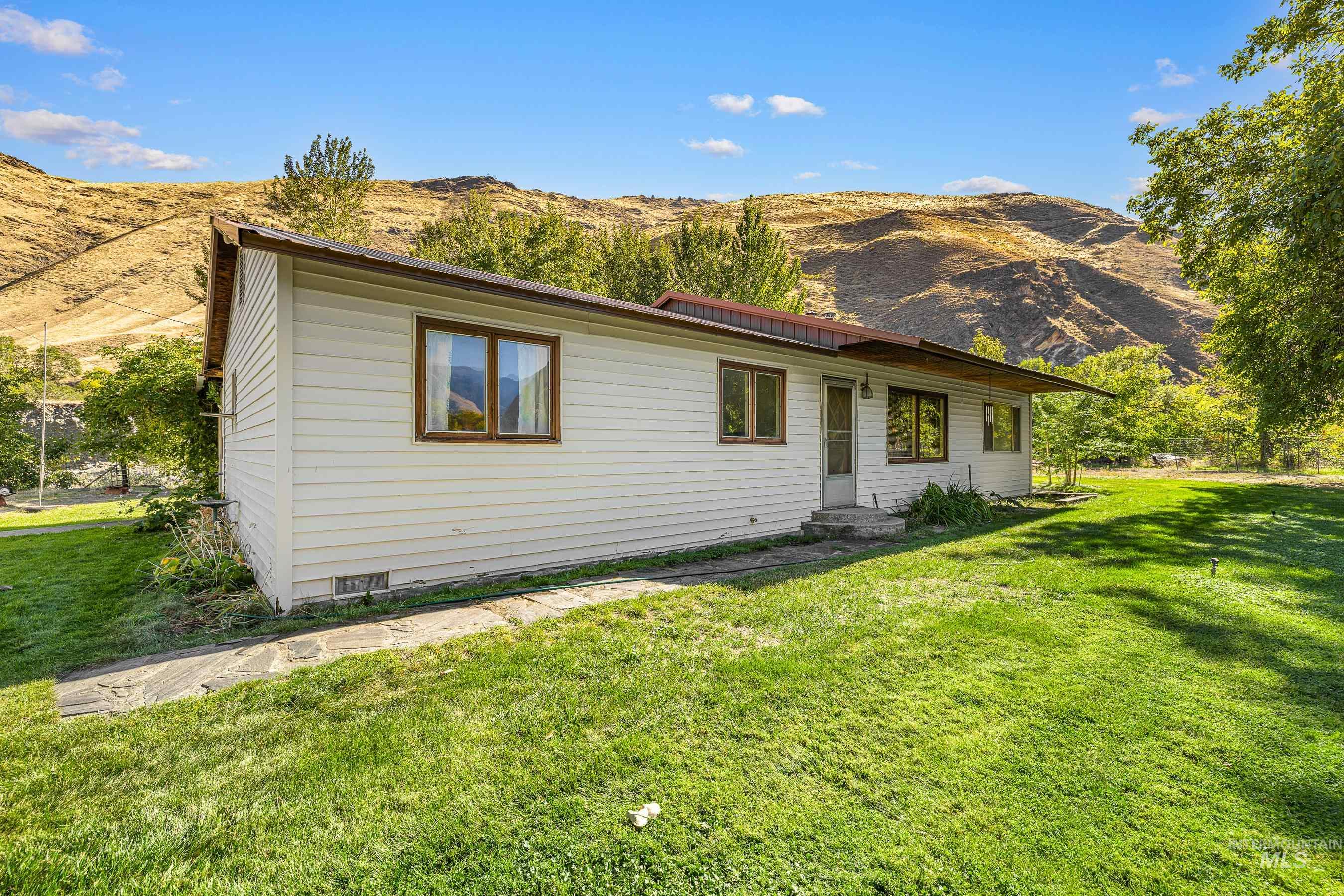 7026 S Highway Riggins, ID 83549 - Photo 14 of 50 Single-story residence featuring white siding, brown-trimmed windows, a reddish-brown roof, and a front entry with concrete steps