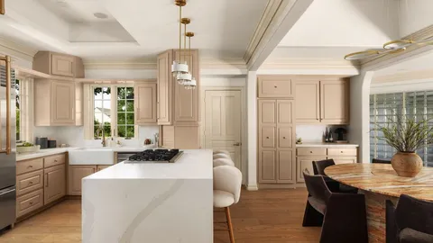 a room with stainless steel appliances kitchen island granite countertop a table chairs in it and wooden floors