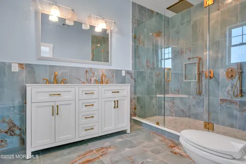 a bathroom with a granite countertop sink a toilet and shower