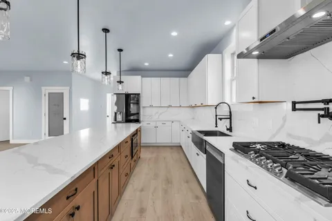 a kitchen with stainless steel appliances a sink a stove and white cabinets