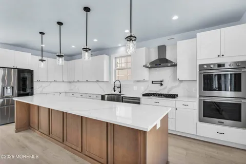 a living room with stainless steel appliances kitchen island granite countertop a sink cabinets and wooden floor