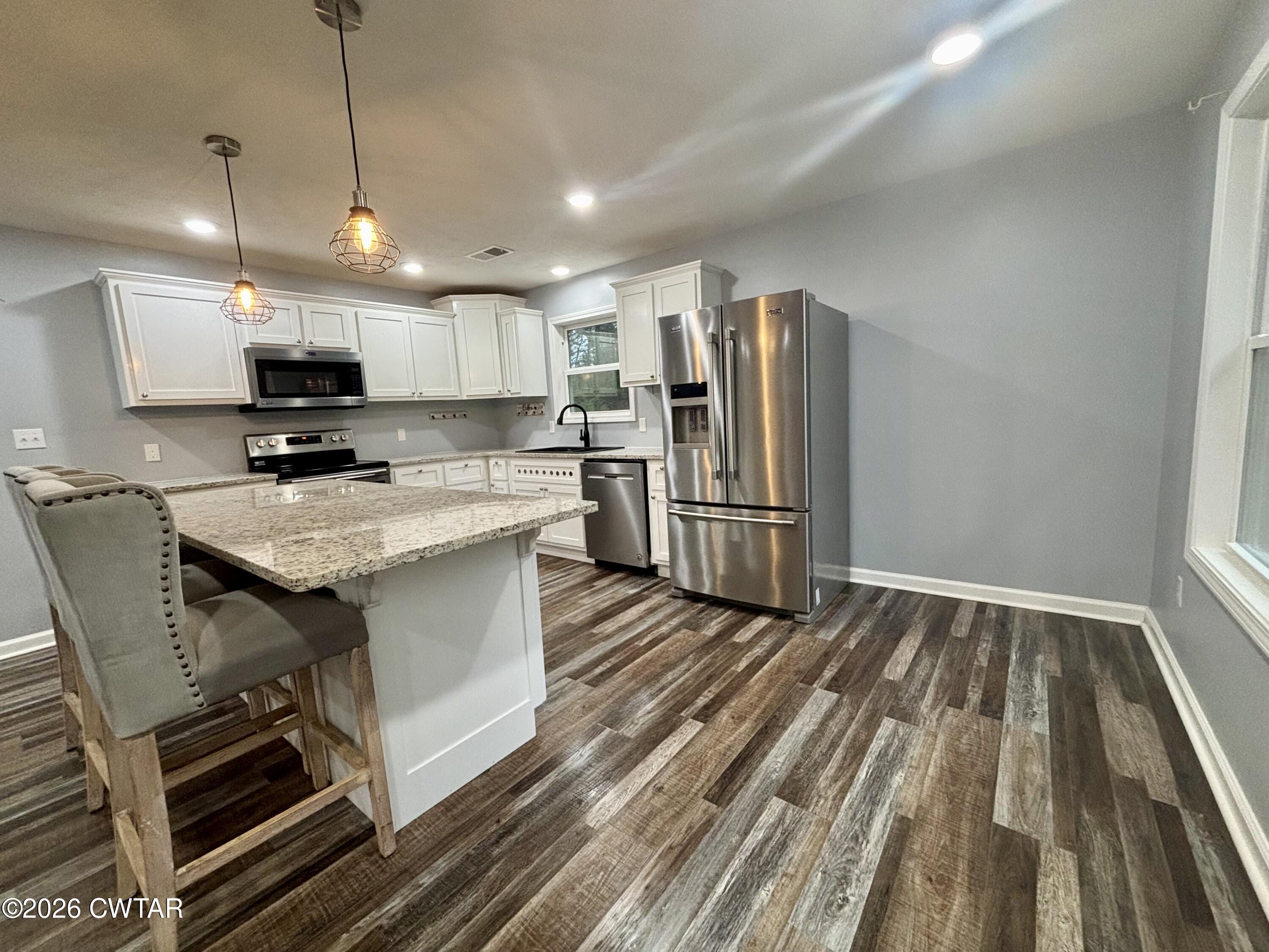 129 Gunner Lane Lexington, TN 38351 - Photo 2 of 19 a kitchen with stainless steel appliances granite countertop a stove top oven a refrigerator a sink and a stove