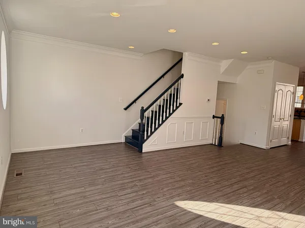 a view of an empty room with wooden floor and stairs