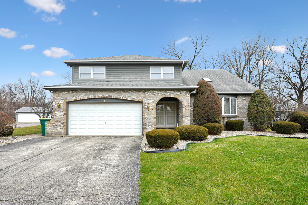 a front view of a house with garden and trees
