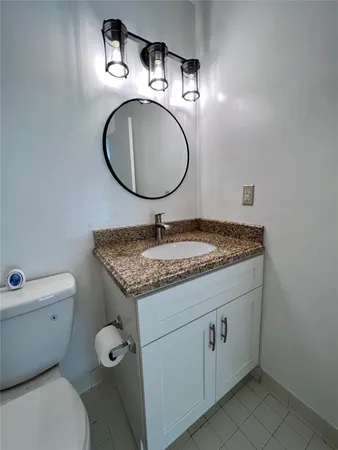 a bathroom with a granite countertop toilet sink and mirror