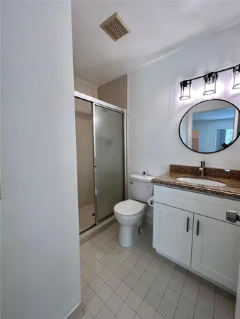 a bathroom with a granite countertop toilet sink and mirror