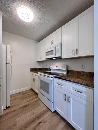 a kitchen with stainless steel appliances granite countertop a stove a sink and white cabinets