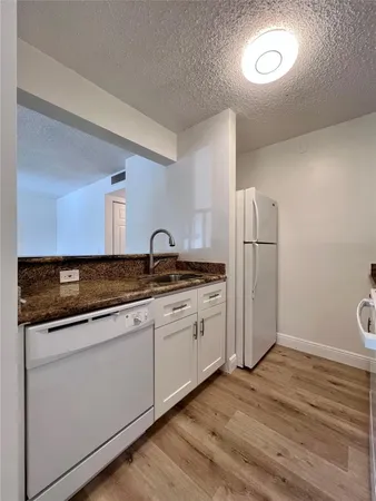 a kitchen with stainless steel appliances granite countertop a sink and a refrigerator
