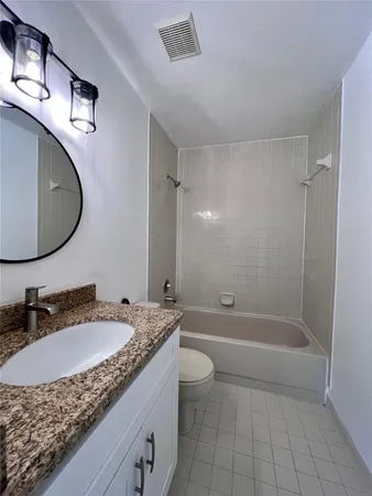 a bathroom with a granite countertop sink a toilet and shower