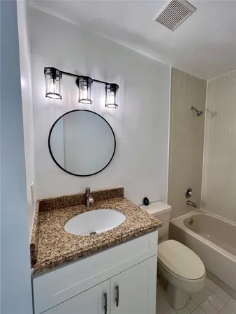 a bathroom with a granite countertop toilet sink and a mirror