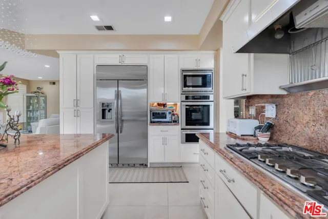 a kitchen with stainless steel appliances granite countertop a stove a sink and a refrigerator