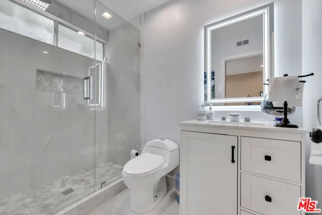 a bathroom with a toilet a sink a mirror and vanity