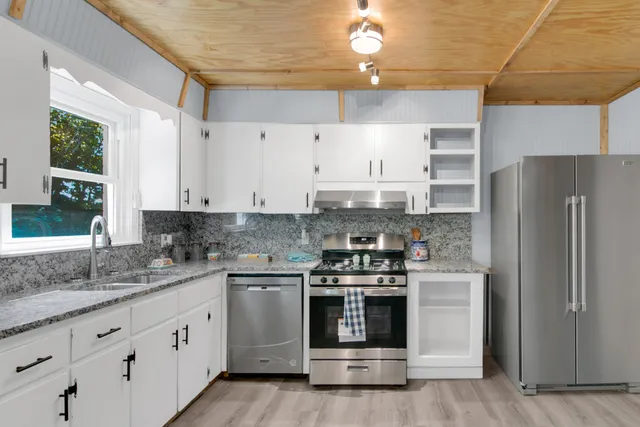 a kitchen with granite countertop white cabinets and white appliances