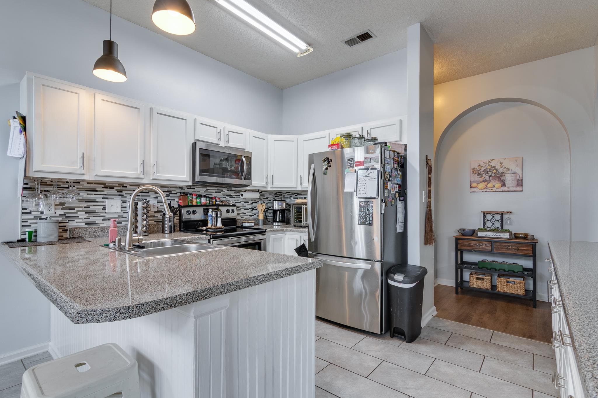 7314 Patsy Circle North Memphis, TN 38125 - Photo 11 of 28 Kitchen featuring a peninsula, white cabinetry, stainless steel appliances, light tile patterned floors, and a kitchen bar