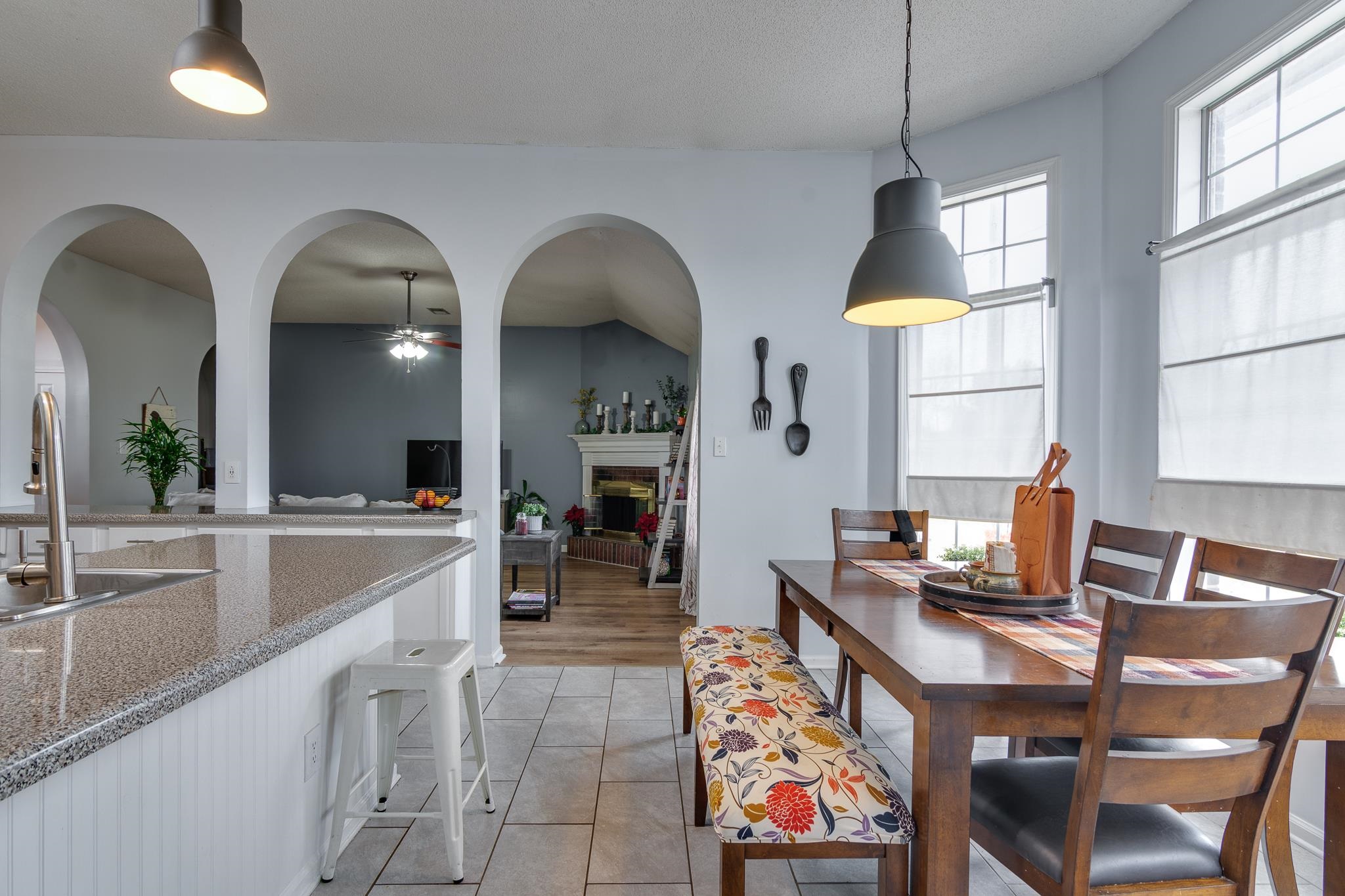 7314 Patsy Circle North Memphis, TN 38125 - Photo 12 of 28 Dining space with a fireplace with raised hearth, ceiling fan, arched walkways, and light tile patterned floors