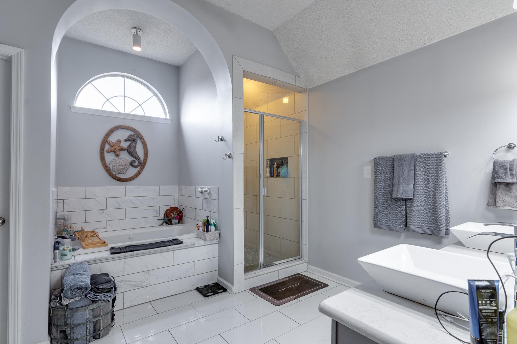 7314 Patsy Circle North Memphis, TN 38125 - Photo 16 of 28 Bathroom featuring vanity, a garden tub, a shower stall, vaulted ceiling, and a textured ceiling