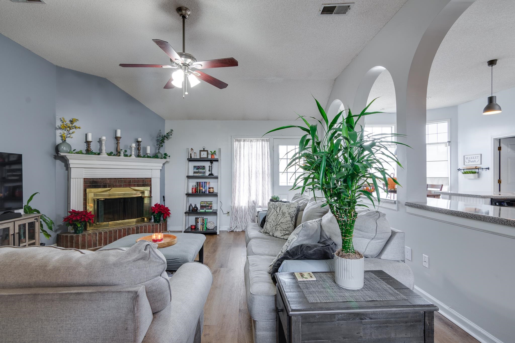 7314 Patsy Circle North Memphis, TN 38125 - Photo 4 of 28 Living area with a brick fireplace, wood finished floors, lofted ceiling, a textured ceiling, and ceiling fan