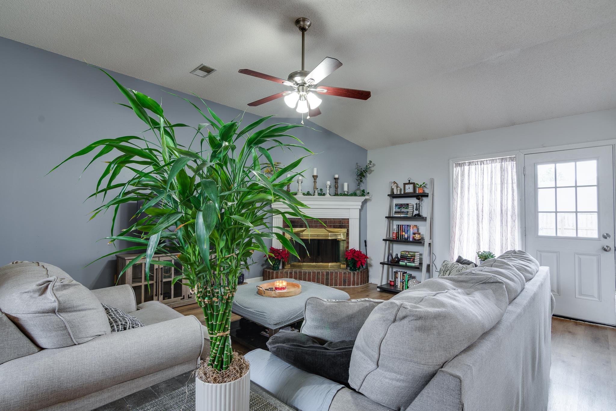 7314 Patsy Circle North Memphis, TN 38125 - Photo 7 of 28 Living room featuring vaulted ceiling, a fireplace, wood finished floors, a ceiling fan, and a textured ceiling