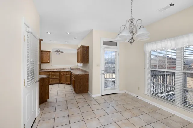 an empty room with wooden floor a ceiling fan and windows