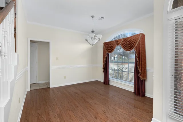an empty room with wooden floor a ceiling fan and windows