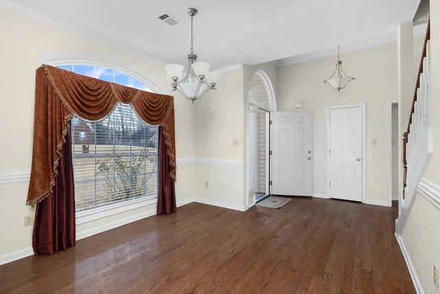 a view of an empty room with wooden floor and a ceiling fan
