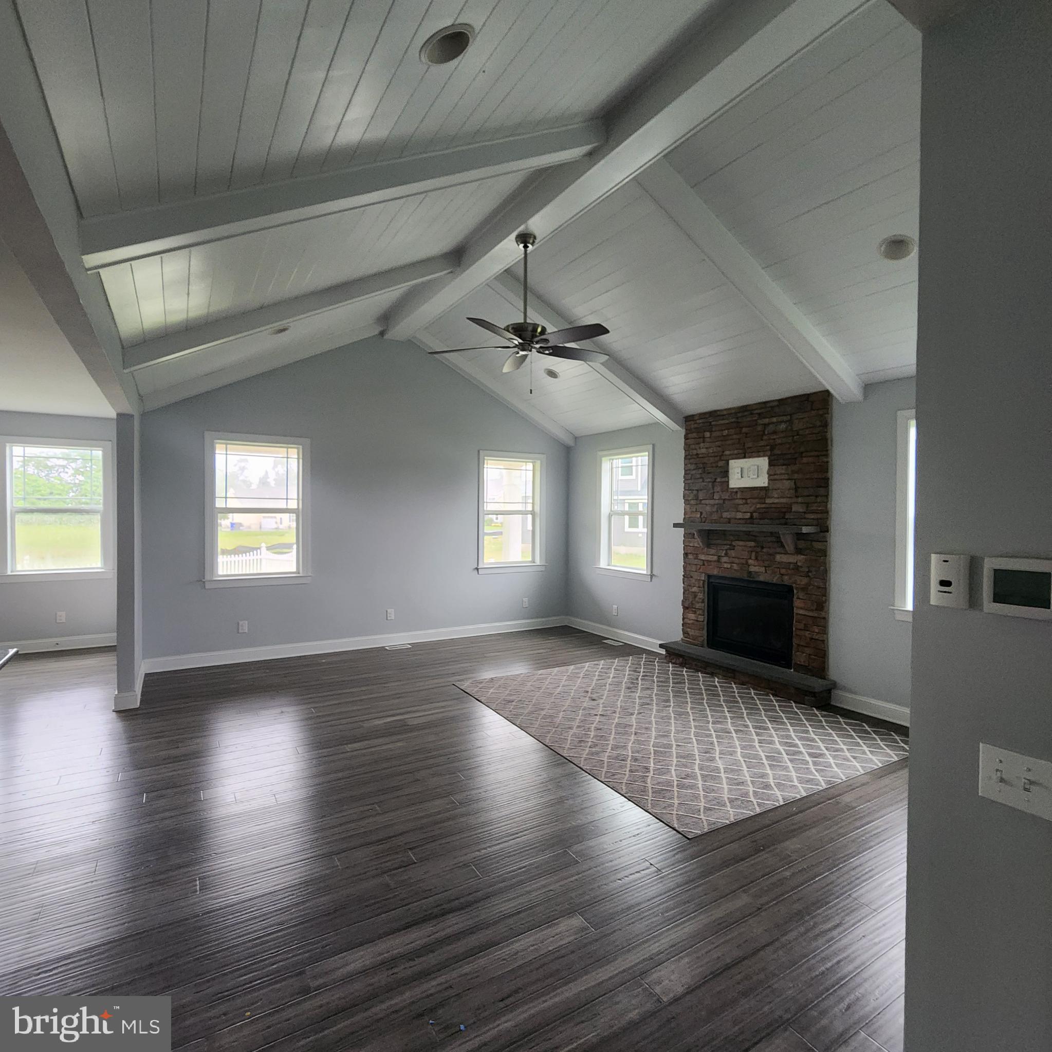 15050 Sandpiper Road Milton, DE 19968 - Photo 9 of 25 an empty room with wooden floor fireplace and windows