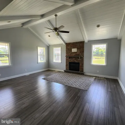 an empty room with wooden floor fireplace and windows