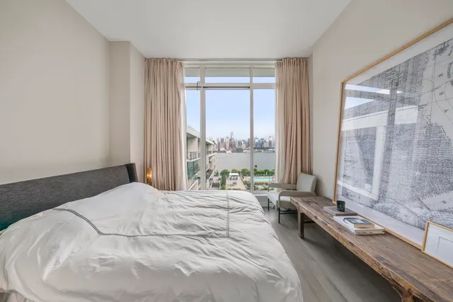 a large white bed sitting in a bedroom next to a window