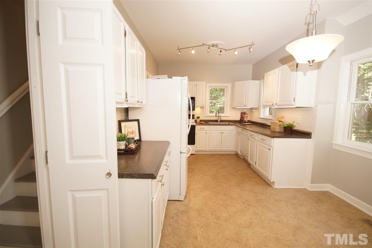 1729 Falls Church Road Raleigh, NC 27609 - Photo 9 of 25 a kitchen with stainless steel appliances granite countertop a stove top oven a sink a refrigerator and white cabinets with wooden floor