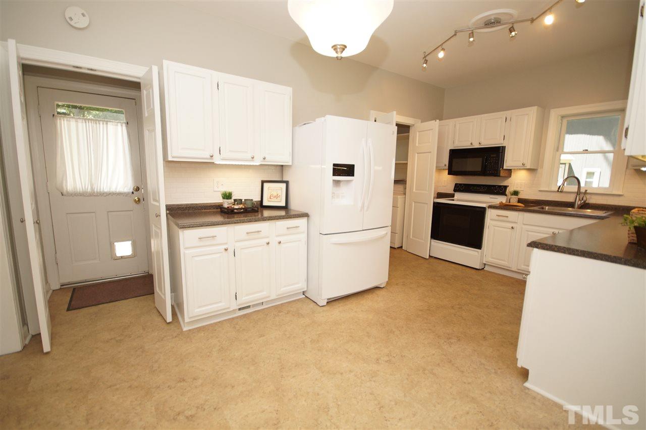 1729 Falls Church Road Raleigh, NC 27609 - Photo 10 of 25 a kitchen with white cabinets and stainless steel appliances