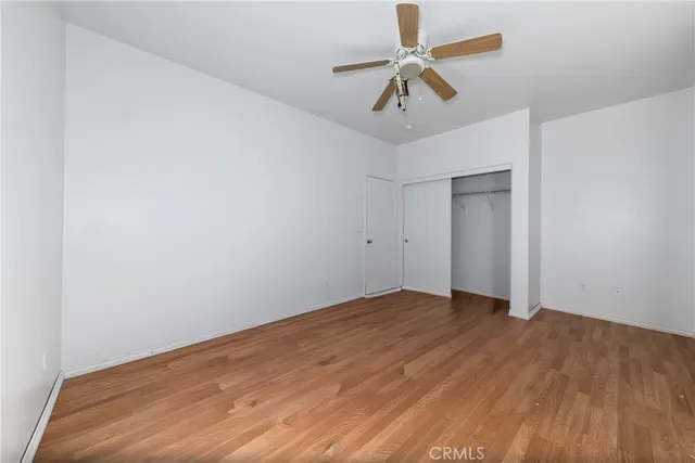 an empty room with wooden floor and ceiling fan
