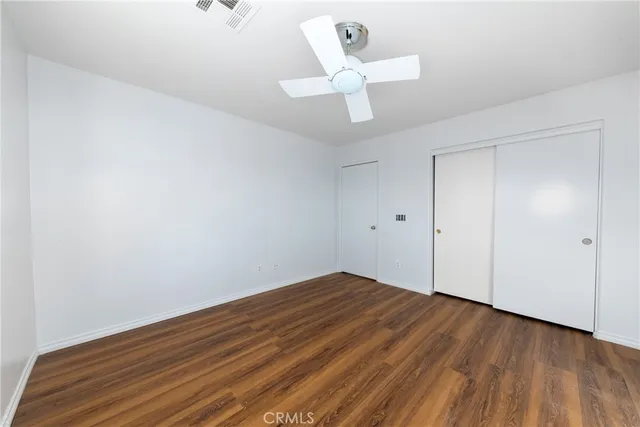 an empty room with wooden floor and ceiling fan