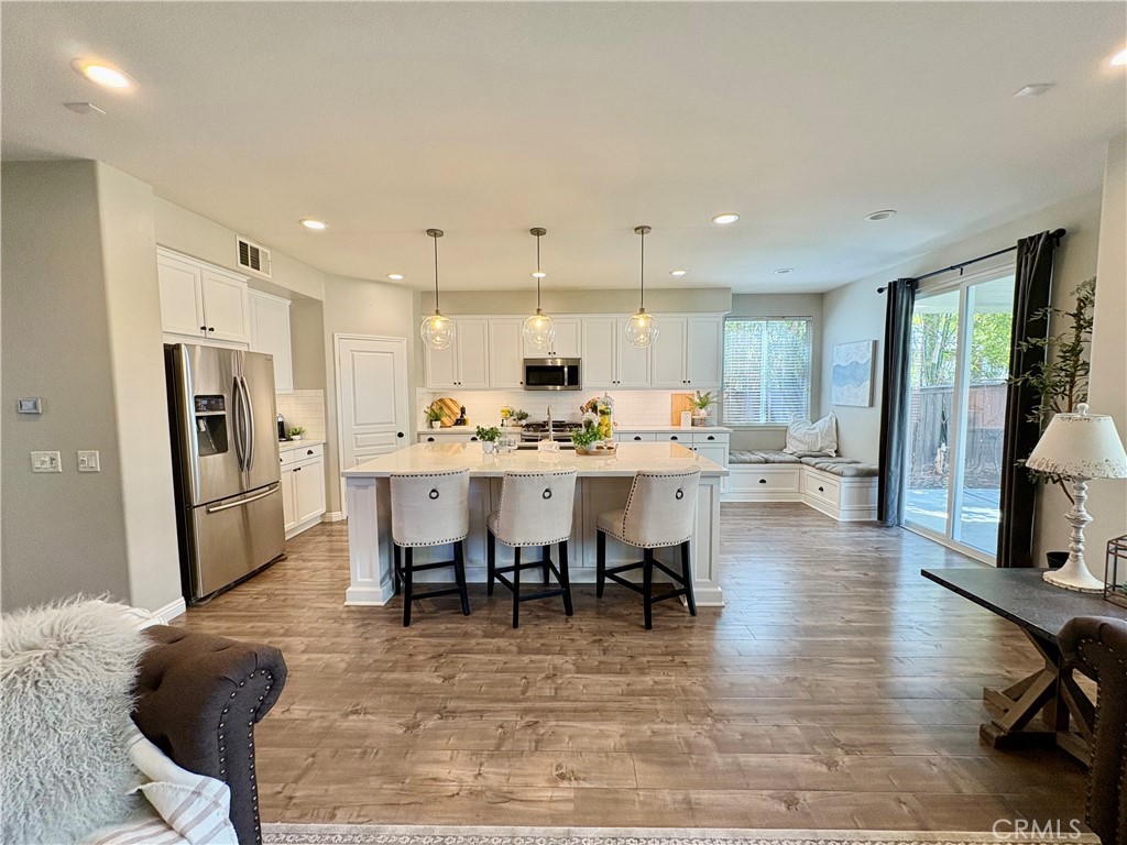 39707 Cambridge Place Temecula, CA 92591 - Photo 4 of 75 a open kitchen with stainless steel appliances kitchen island granite countertop a refrigerator a stove a sink a dining table and chairs with wooden floor