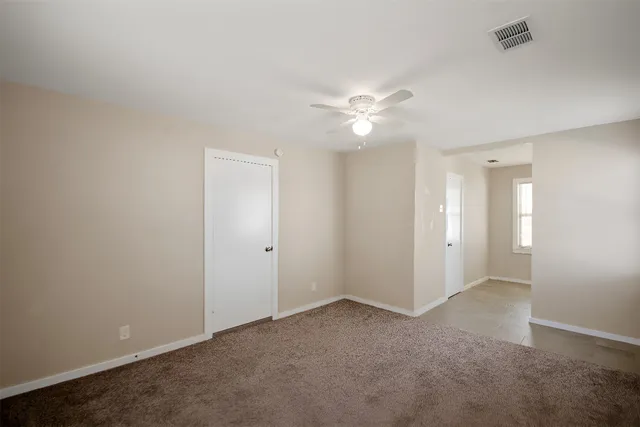 an empty room with a ceiling fan and a window