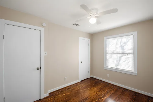 a view of an empty room with a window and wooden floor