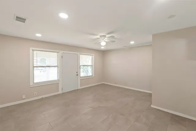 an empty room with windows and chandelier fan