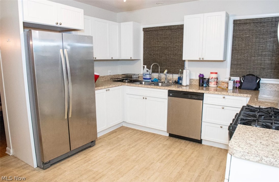 6714 Trenholm Road Youngstown, OH 44512 - Photo 6 of 22 Kitchen with light hardwood / wood-style floors, appliances with stainless steel finishes, white cabinets, and sink