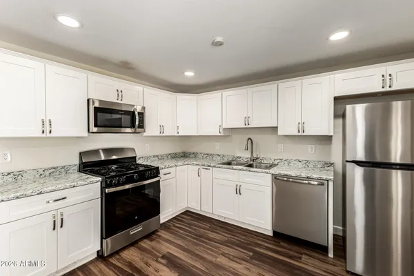 a kitchen with granite countertop a refrigerator stove and microwave