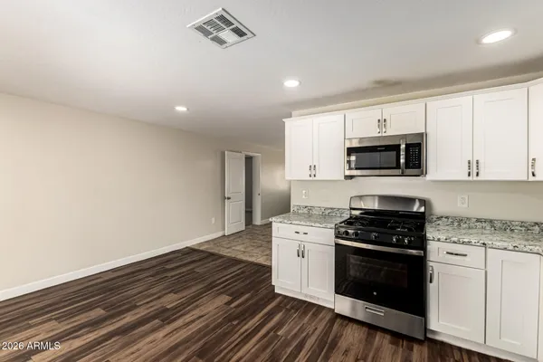 a kitchen with granite countertop a stove top oven and cabinets
