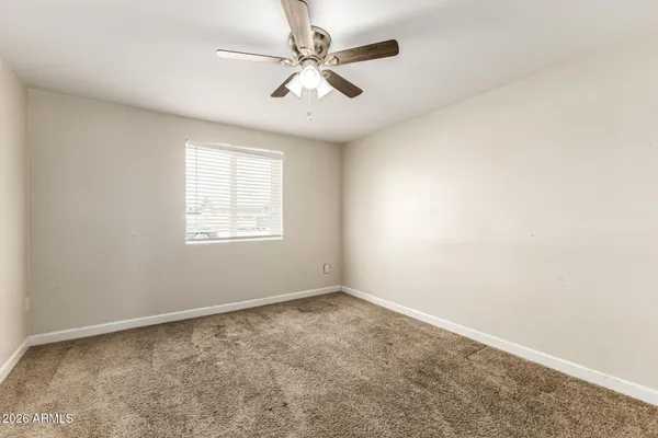 an empty room with windows and fan
