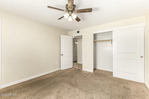 an empty room with closet and a ceiling fan